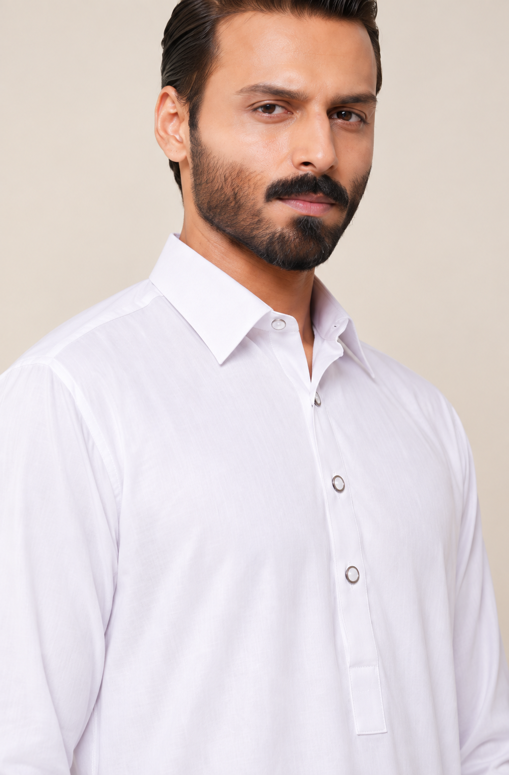 A man wearing a white long-sleeve button-down dress shirt, shown from the chest up against a plain light beige studio background.